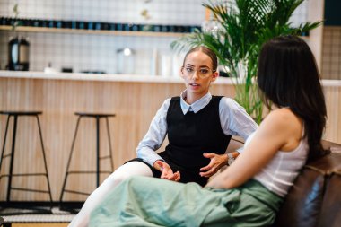 modern ofisindeki deri kanepede oturan iki iş kadınları