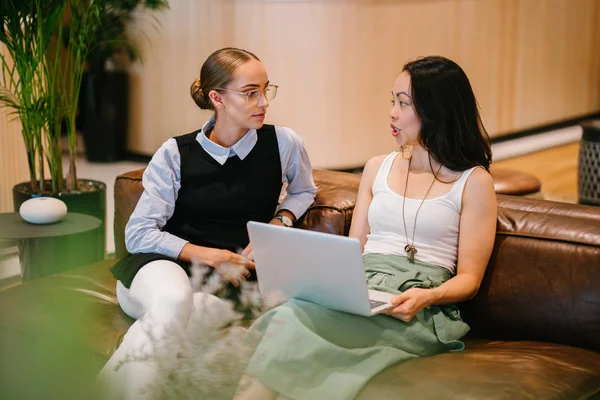 iki iş kadınları modern ofisindeki deri kanepede oturan proje tartışıyor  