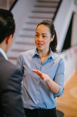 Merdiven ile modern ofis proje ayakta arka plan üzerinde tartışırken iki Asya iş adamları