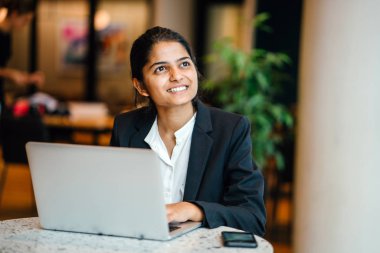 modern ofis, masada oturan dizüstü bilgisayar üzerinde çalışan takım elbiseli Genç emin iş kadını uzağa arıyorsunuz