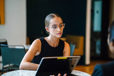 gülümseyen ve konuşurken masada oturan genç kadın iş ortakları 
