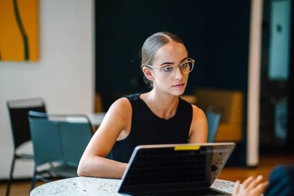 young female business partners sitting at table smiling and talking