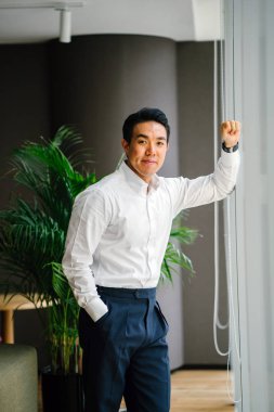 düşünceli işadamı zemin üzerine yeşil bitki ile modern ofis penceresinde yanında ayakta