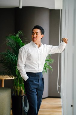 düşünceli işadamı zemin üzerine yeşil bitki ile modern ofis penceresinde yanında ayakta