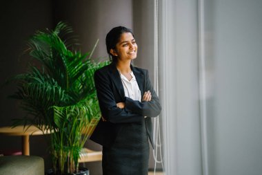 Toplantı salonunun içinde pencere adlı genç gülümseyen iş kadını silah ile ayakta portresi geçti
