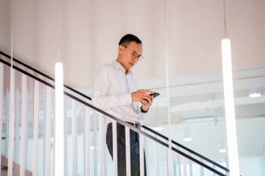 Asya adam modern ofis adımlarla yürürken smartphone holding