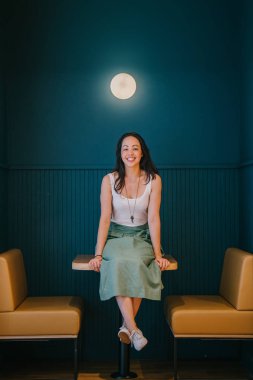 masada oturan gülüyor şık Asyalı kadın portresi tam uzunlukta