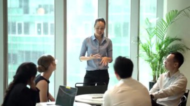 ayakta ve konuşma, sunum yapma Asyalı kadın modern ofisinde oturan projeleri tartışmak iş adamları