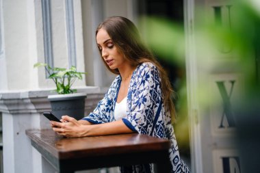 bokeh yeşil yaprakları ile tencerede çiçekli masada oturan uzun saçlı güzel şık kadın portresi