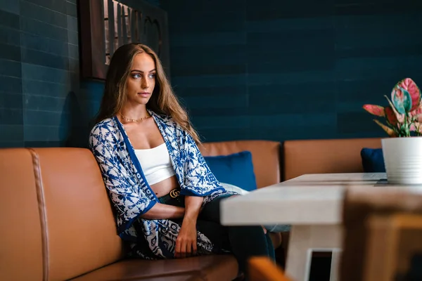 şık genç kadın uzun saçlı kafede masada oturan portresi