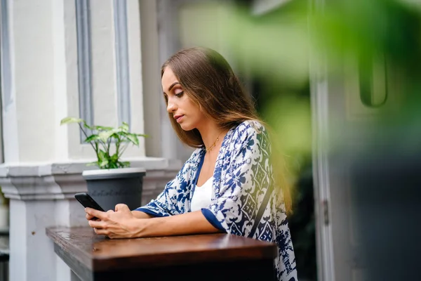 bokeh yeşil yaprakları ile tencerede çiçekli masada oturan uzun saçlı güzel şık kadın portresi