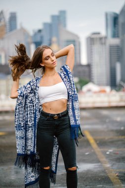 üst ve arka plan üzerinde gökdelenler onun uzun saç ayakta dokunmadan kot giymiş şık genç kadın
