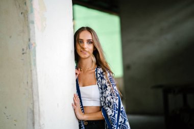 Üst ve beton arka planı poz ve uzağa bakarak eşarp giyen güzel genç kadın portresi