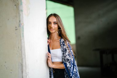 Üst ve beton arka planı poz ve kameraya gülümseyen eşarp giyen güzel genç kadın portresi.