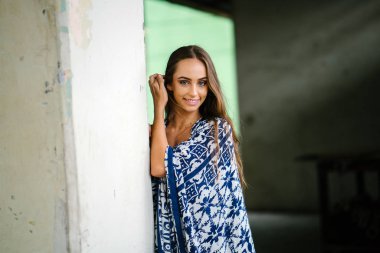 Beton arka planı poz ve kameraya gülümseyen uzun saçları dokunmadan güzel genç kadın portresi.