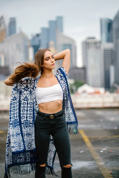 üst ve arka plan üzerinde gökdelenler onun uzun saç ayakta dokunmadan kot giymiş şık genç kadın