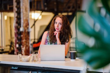 düşünceli işkadını kafede masada oturan laptop çalışma