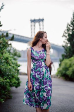 riverside Köprüsü arka plan üzerinde yürürken ihale kıvırcık saçlı esmer kadın