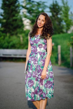 dizüstü bilgisayar açık havada ayakta tutan kıvırcık saçlı esmer kadın 