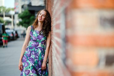 tuğla duvar ayakta ve gülümsüyor kıvırcık saçlı Genç güzel kadın