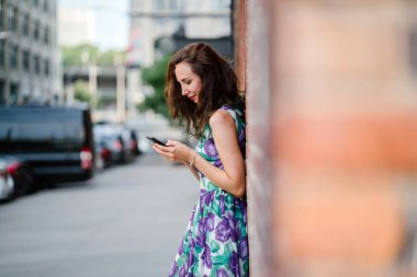 turuncu tuğla duvara Smartphone ayakta kullanan güzel esmer kadın 