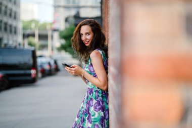 turuncu tuğla duvara Smartphone ayakta kullanan güzel esmer kadın 