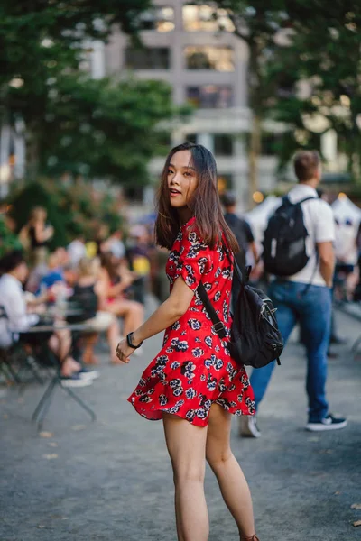 道を歩いてバックパックで赤いドレスの若い女性 — ストック写真