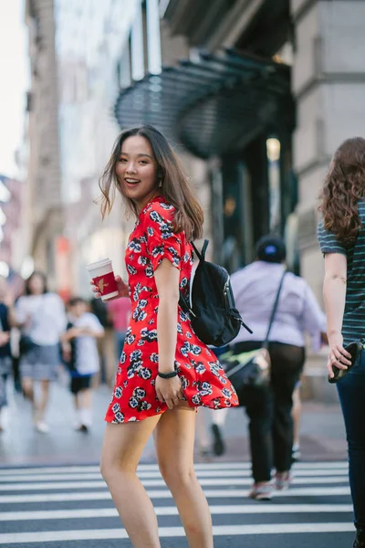 道を歩いてコーヒーのカップで赤いドレスの若い女性 — ストック写真