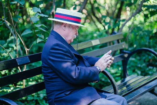 Senior businessman wearing suit and using smartphone in city park