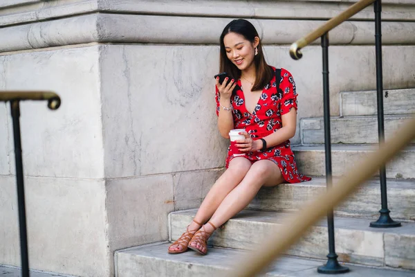 手順にコーヒーのカップを持つ携帯電話に赤いドレスの若い女性 — ストック写真