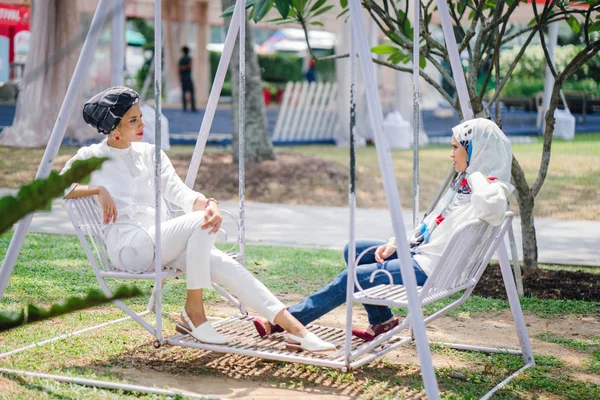 Salıncak üzerinde baş eşarp iki genç ve çekici Müslüman kadın 