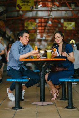 İyi görünümlü bir Çin Asya çift bir aperatif bir hawker merkezinde hafta sonu Singapur'da, Asya zevk portresi. Şeker kamışı suyu ve kızarmış muz tadını çıkarıyor.