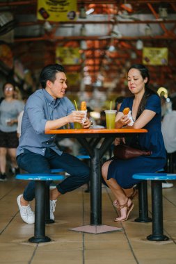 İyi görünümlü bir Çin Asya çift bir aperatif bir hawker merkezinde hafta sonu Singapur'da, Asya zevk portresi. Şeker kamışı suyu ve kızarmış muz tadını çıkarıyor.