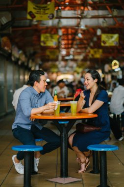 İyi görünümlü bir Çin Asya çift bir aperatif bir hawker merkezinde hafta sonu Singapur'da, Asya zevk portresi. Şeker kamışı suyu ve kızarmış muz tadını çıkarıyor.
