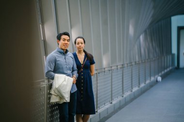 Bir Asya Çin portresi çift bir tarihte, hafta sonu. Genç, yakışıklı ve iyi giyimli adam ve kadın bir şık yazlık elbise giyiyor. Bir köprüde olduklarını.