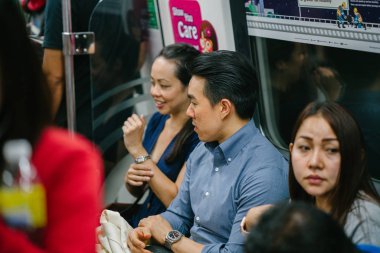 Metroda oturan genç Asyalı çift.