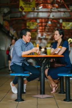 İyi görünümlü bir Çin Asya çift bir aperatif bir hawker merkezinde hafta sonu Singapur'da, Asya zevk portresi. Şeker kamışı suyu ve kızarmış muz tadını çıkarıyor.