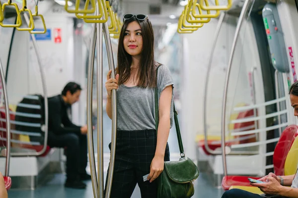young and pretty Japanese Asian tourist woman on a train in Asia while on vacation.