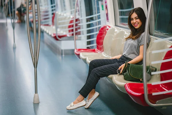 young and pretty Japanese Asian tourist woman sitting on a train in Asia while on vacation. She is cute, attractive and is smiling happily as she relaxes in her seat.