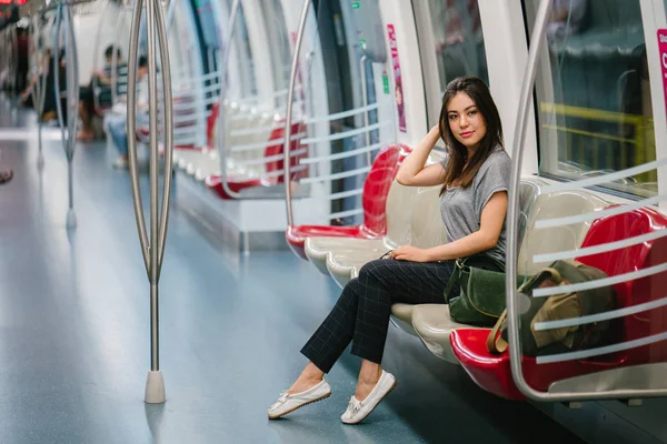 young and pretty Japanese Asian tourist woman sitting on a train in Asia while on vacation. She is cute, attractive and is smiling happily as she relaxes in her seat.