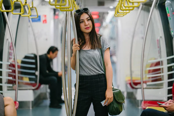 young and pretty Japanese Asian tourist woman on a train in Asia while on vacation.