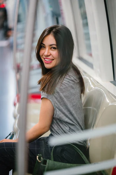young and pretty Japanese Asian tourist woman sitting on a train in Asia while on vacation. She is cute, attractive and is smiling happily as she relaxes in her seat.