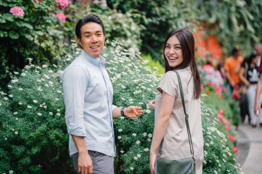 Genç ve çekici bir Asya çift durdurmak çiçekler bir parkta gündüz kokusu. 