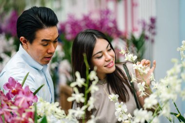 Genç ve çekici bir Asya çift durdurmak çiçekler bir parkta gündüz kokusu. 