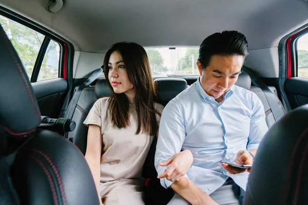 つの若いアジア ビジネス人々 車の後部座席に座っているし その先に彼らは予約乗車乗車出身アプリケーション経由で運転されます — ストック写真