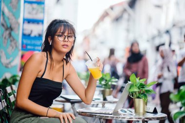 dizüstü bilgisayar kullanarak ve açık Cafe portakal suyu içme Genç Asyalı kadın 