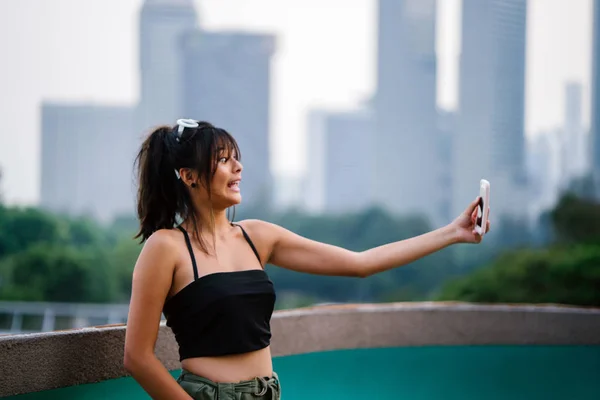 Young asian woman in casual clothes making selfie on smartphone