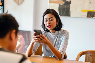 Kafede cep telefonu kullanan iki genç kadın.