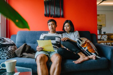 Malay çift kanepede oturup beraber okuduk. Genç, çekici ve rahat onlar onların oturma odasında onların kanepede birlikte hafta sonu zevk gibi olduklarından.