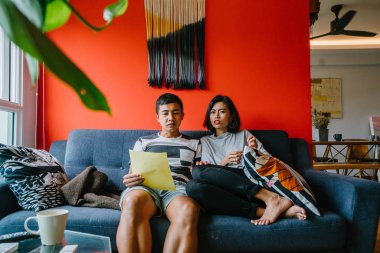 Malay çift kanepede oturup beraber okuduk. Genç, çekici ve rahat onlar onların oturma odasında onların kanepede birlikte hafta sonu zevk gibi olduklarından.